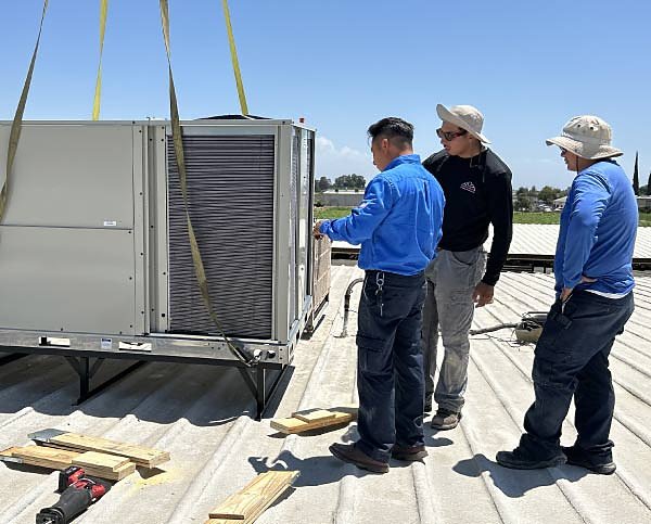 Mechanical Air technicians setting a rooftop package unit in the Central Valley